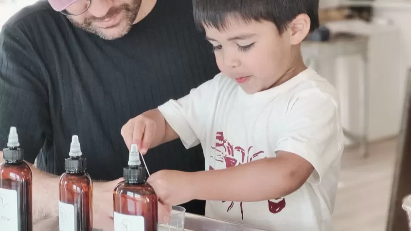 Younger child making a candle with his dad