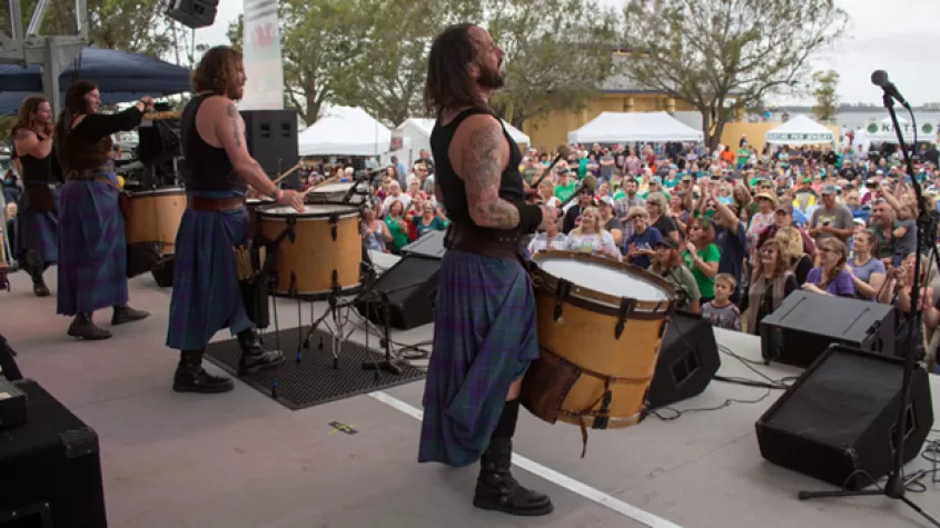 Performers on stage looking out at audience in chairs on lawn
